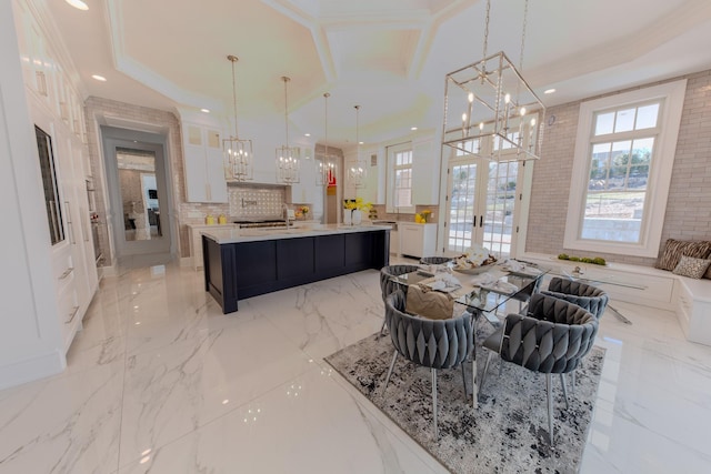 kitchen featuring a chandelier, white cabinets, marble finish floor, light countertops, and a raised ceiling