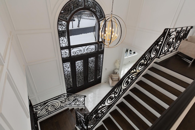 entrance foyer with stairs, marble finish floor, french doors, and a notable chandelier