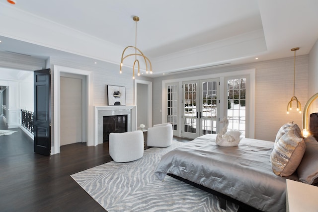 bedroom featuring a fireplace, wood finished floors, access to exterior, french doors, and a tray ceiling