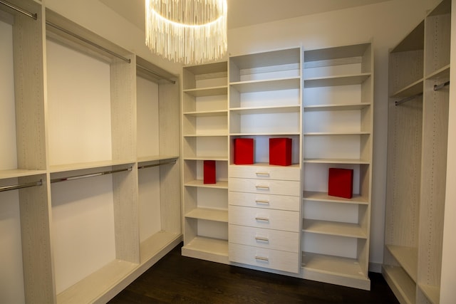 spacious closet with dark wood-style floors and a notable chandelier