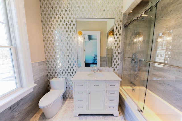 bathroom with enclosed tub / shower combo, vanity, toilet, and tile walls