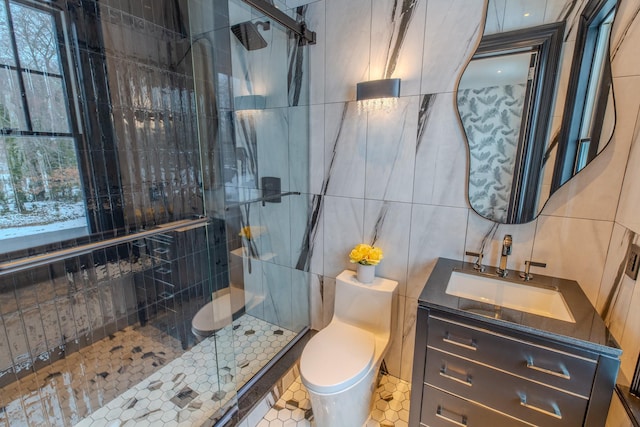 bathroom with a stall shower, toilet, tile patterned flooring, vanity, and tile walls