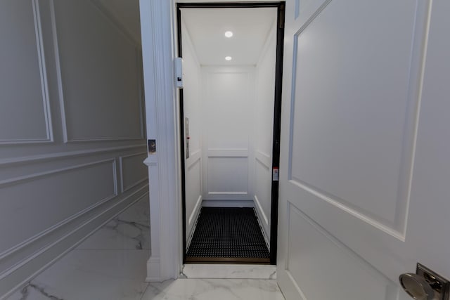 corridor with marble finish floor, a decorative wall, elevator, and recessed lighting