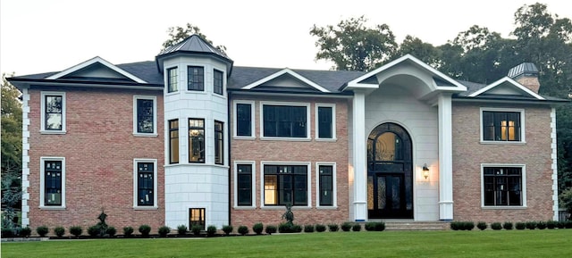 view of front of house featuring a front yard, brick siding, and a chimney