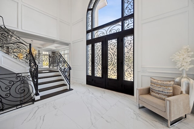 foyer featuring a decorative wall, marble finish floor, and stairway