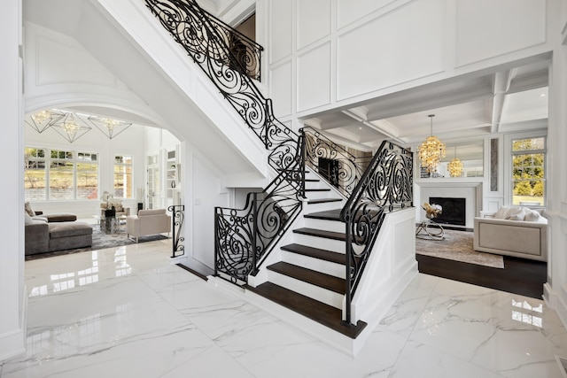 stairs featuring a notable chandelier, marble finish floor, and a decorative wall