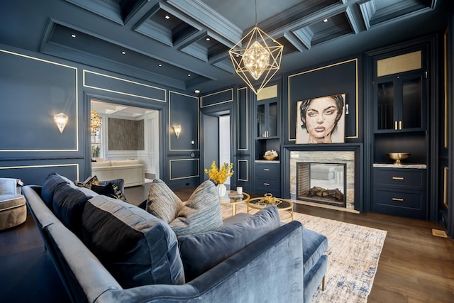 cinema room with a chandelier, a decorative wall, crown molding, and coffered ceiling