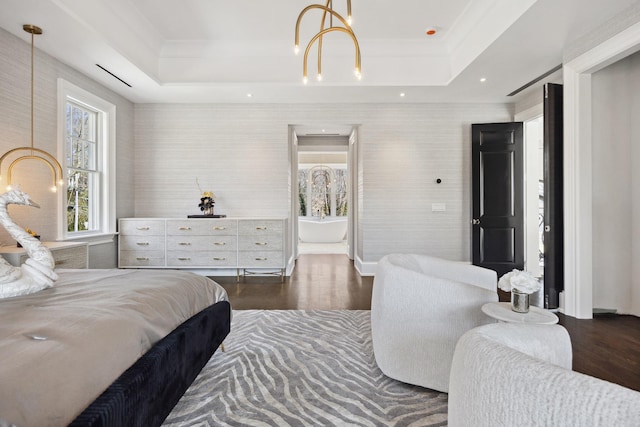 bedroom with a tray ceiling, wood finished floors, and a notable chandelier