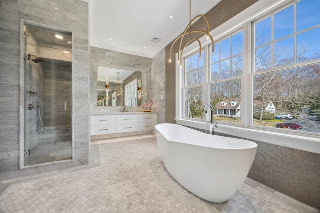 bathroom with a stall shower, a soaking tub, vanity, and visible vents