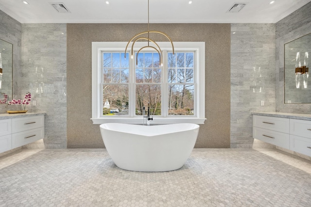 bathroom featuring visible vents, tile walls, vanity, and a soaking tub