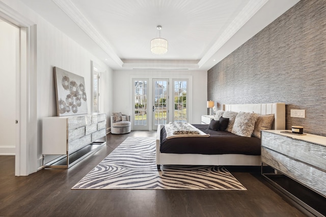 bedroom with a tray ceiling, access to exterior, baseboards, and wood finished floors