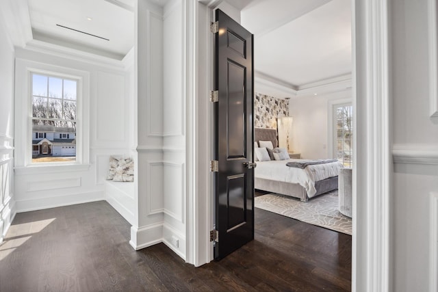 corridor featuring dark wood-type flooring, a tray ceiling, and ornamental molding