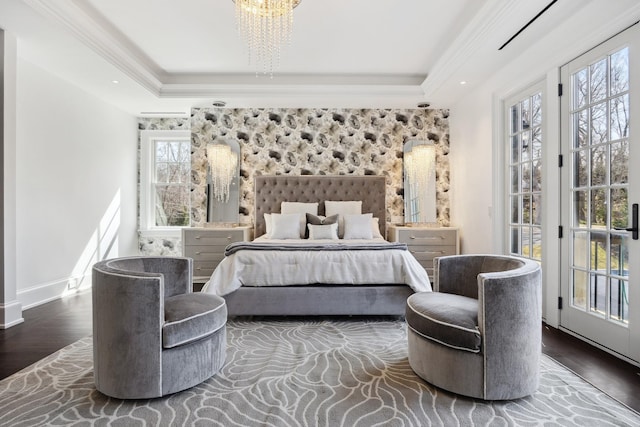 bedroom with baseboards, a notable chandelier, crown molding, a tray ceiling, and wood finished floors