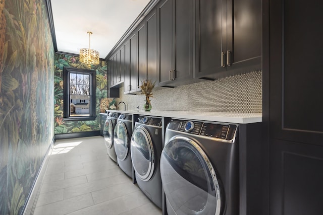 washroom featuring cabinet space, washer and clothes dryer, an inviting chandelier, and wallpapered walls