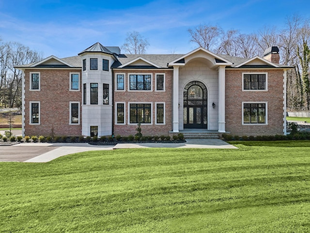 view of front of home featuring a front yard, brick siding, and a chimney