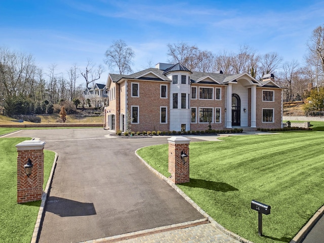 neoclassical home with a front yard, brick siding, and aphalt driveway