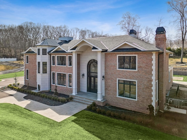 view of front of house with brick siding, a front yard, and a chimney