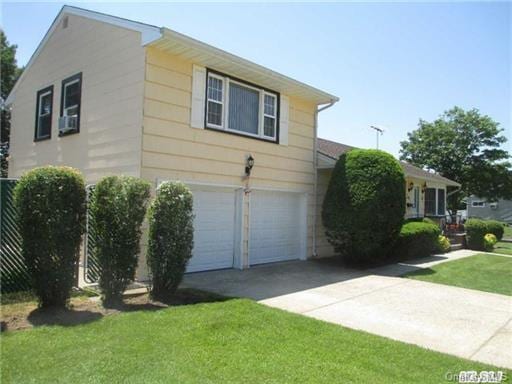 view of side of property with an attached garage, concrete driveway, and a yard