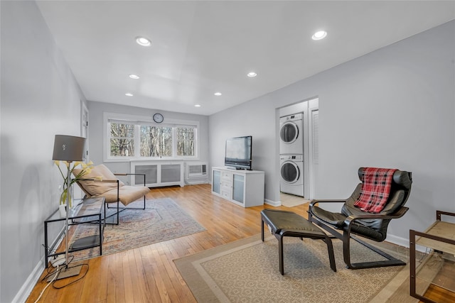 living area featuring stacked washer / dryer, light wood-style flooring, baseboards, and recessed lighting