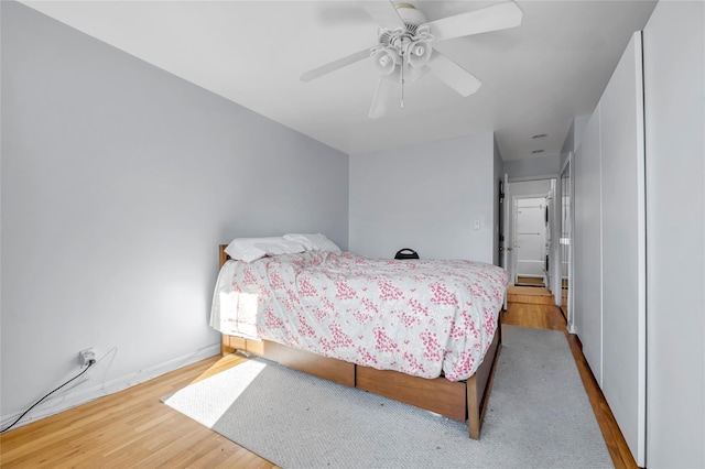 bedroom with light wood-type flooring, ceiling fan, and baseboards