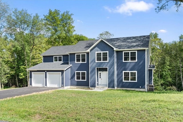 colonial inspired home featuring a garage, aphalt driveway, and a front lawn