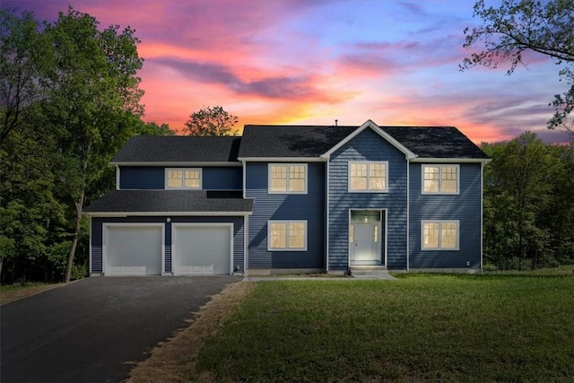 view of front of home featuring a garage, aphalt driveway, a lawn, and entry steps