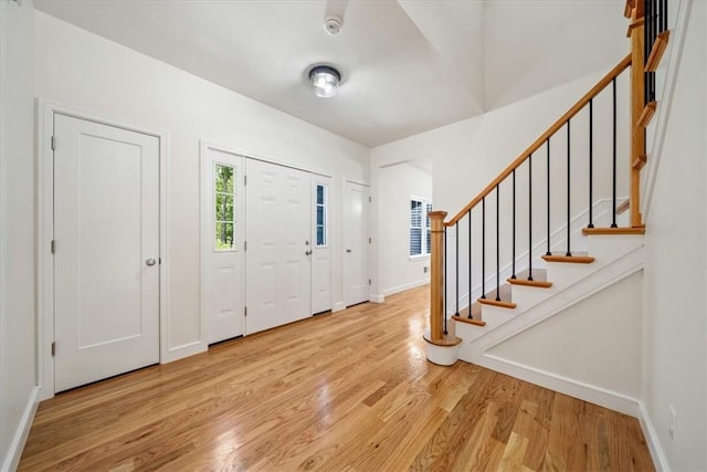 entryway featuring light wood-type flooring, stairway, and baseboards