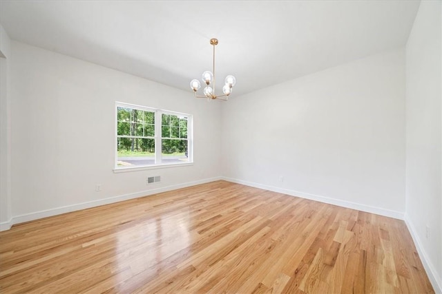 unfurnished room with light wood-style flooring, visible vents, a chandelier, and baseboards