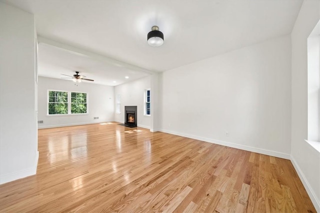 unfurnished living room with light wood finished floors, a fireplace with flush hearth, a ceiling fan, and baseboards