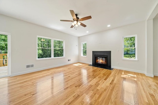 unfurnished living room featuring light wood-style flooring, visible vents, baseboards, and a fireplace with flush hearth