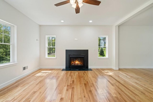 unfurnished living room with recessed lighting, visible vents, a fireplace with flush hearth, light wood-type flooring, and baseboards