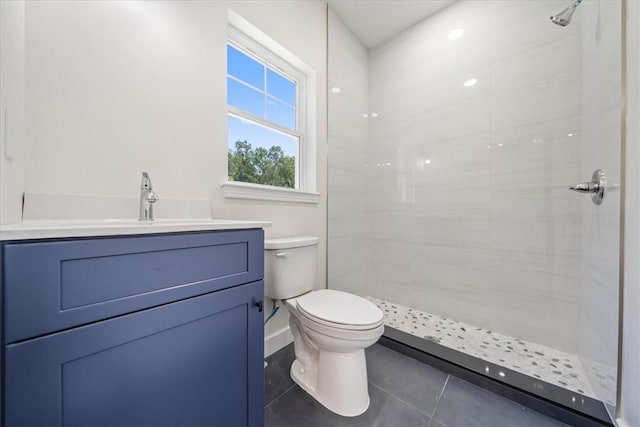 bathroom featuring toilet, tile patterned floors, tiled shower, and vanity