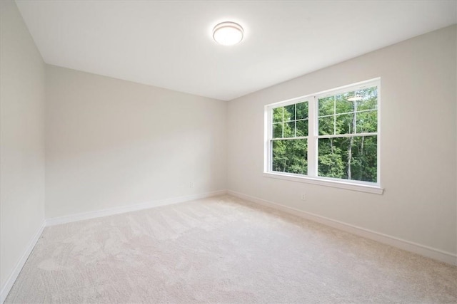 empty room featuring light carpet and baseboards