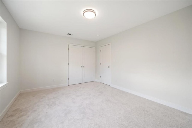 unfurnished room featuring visible vents, baseboards, and light colored carpet