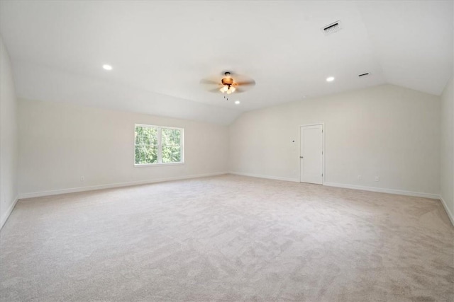 empty room featuring light carpet, visible vents, baseboards, lofted ceiling, and ceiling fan