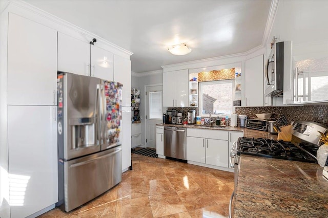 kitchen with white cabinets, appliances with stainless steel finishes, a sink, crown molding, and backsplash