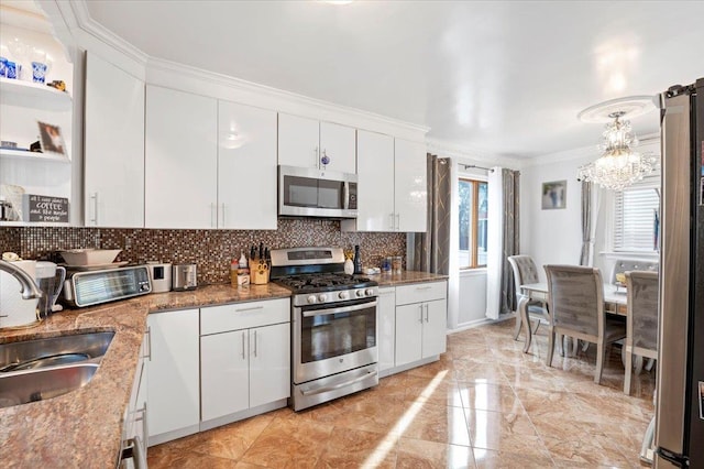 kitchen featuring appliances with stainless steel finishes, backsplash, a sink, and white cabinets