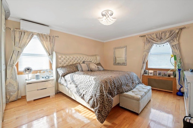 bedroom with a wall unit AC, light wood-style floors, and ornamental molding