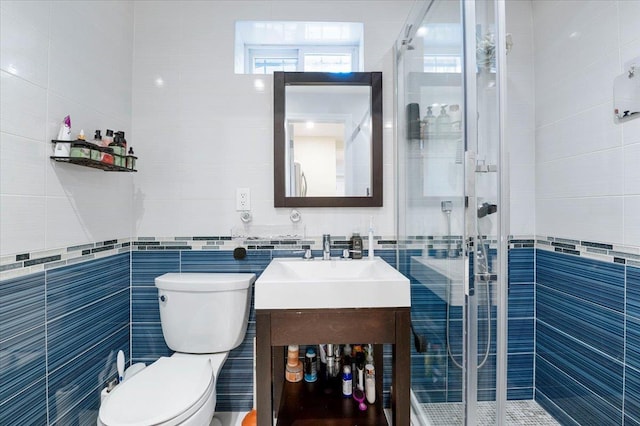 bathroom featuring a stall shower, vanity, and tile walls