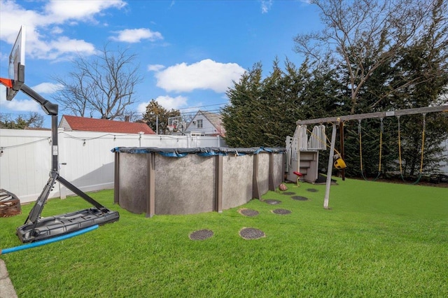 view of yard featuring a playground, a covered pool, and fence