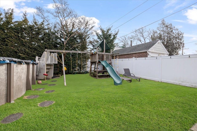 view of playground with a lawn and a fenced backyard