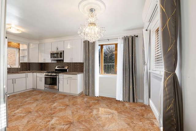 kitchen with dark countertops, decorative backsplash, appliances with stainless steel finishes, white cabinets, and a chandelier