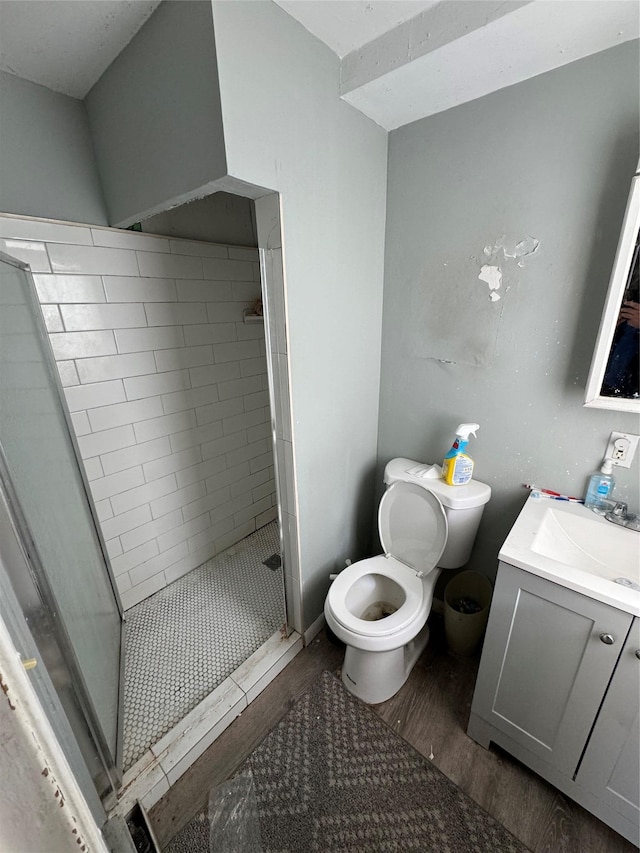 bathroom with toilet, a stall shower, wood finished floors, and vanity