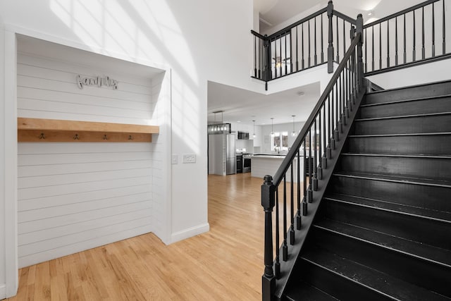 61 Surrey St, Rock Hill, NY 12775 - staircase with wood finished floors, wooden walls, a chandelier, baseboards, and a towering ceiling