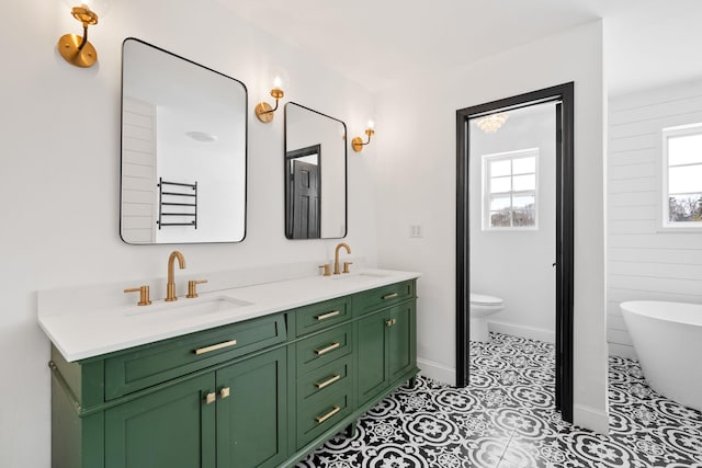 61 Surrey St, Rock Hill, NY 12775 - full bath with double vanity, a freestanding bath, toilet, tile patterned flooring, and baseboards
