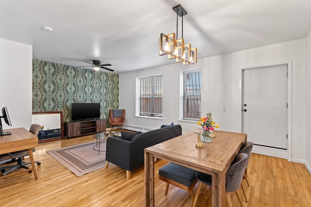 living area featuring wallpapered walls, light wood-style flooring, an accent wall, baseboards, and ceiling fan with notable chandelier