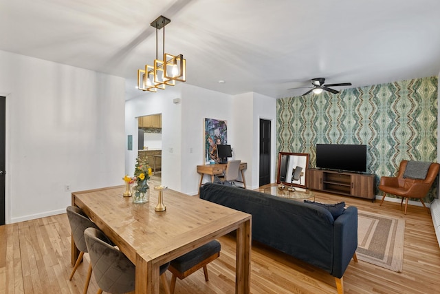 dining space featuring wallpapered walls, baseboards, light wood-style flooring, an accent wall, and ceiling fan