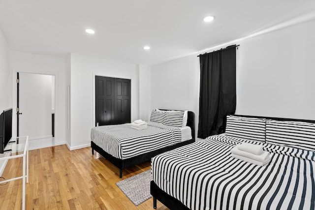 bedroom with light wood finished floors, baseboards, a closet, and recessed lighting