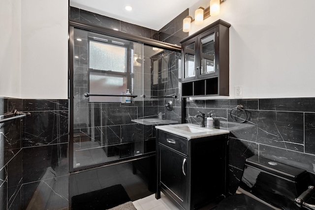 bathroom featuring a stall shower, tile patterned flooring, vanity, and tile walls