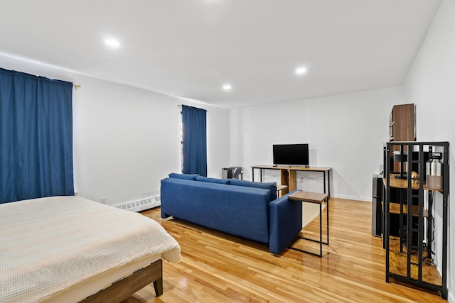 bedroom with light wood-type flooring, a baseboard radiator, and recessed lighting